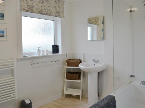 a white bathroom with a sink and a window at Cotters Cottage - Uk10922 in Whithorn