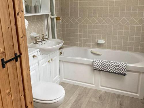a bathroom with a sink and a tub and a toilet at Neigwl View in Dinas