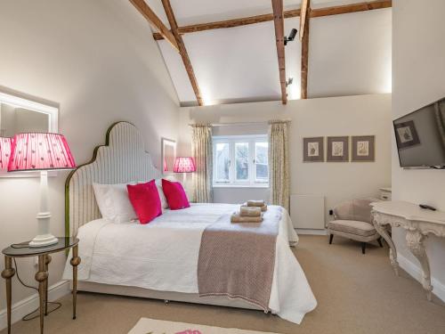 a bedroom with a large white bed with red pillows at Orchard Farmhouse in Wighton