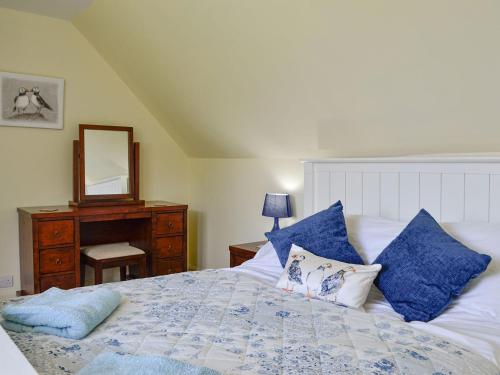 a bedroom with a bed with blue pillows and a mirror at The Brewers Cottage in Mauchline