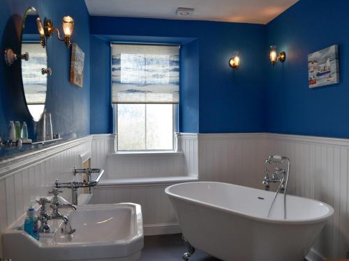 uma casa de banho azul com uma banheira e um lavatório em The Brewers Cottage em Mauchline