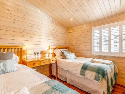 a bedroom with two beds and a wooden wall at Walnut Lodge-uk37595 in Willington