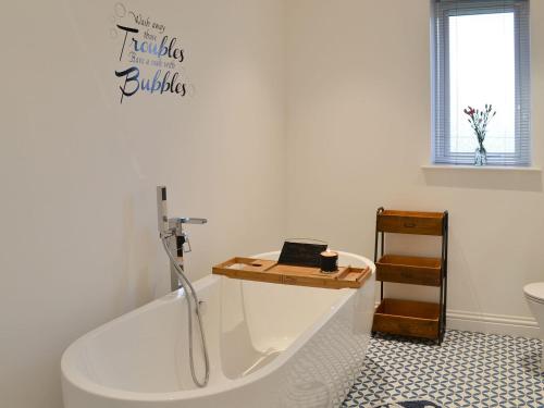 a bathroom with a bath tub with a laptop on it at West Kilbride in Pollachar