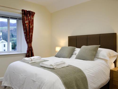 - une chambre avec un grand lit blanc et une fenêtre dans l'établissement Mary Rook Cottage - Uk1369, à Keswick
