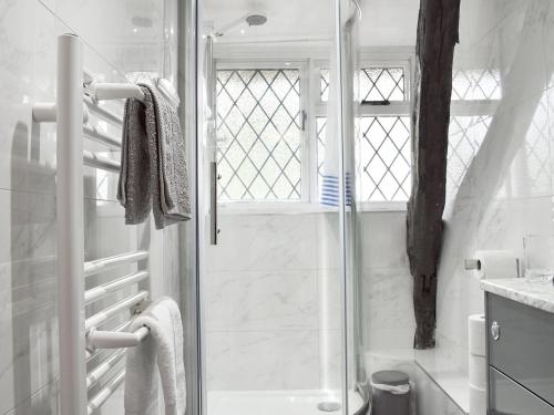 a white bathroom with a shower and a glass door at Primrose Cottage in Diseworth