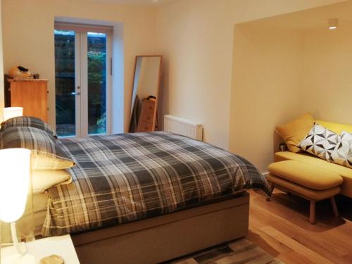 a bedroom with a bed and a chair at Kilbowie Retreat in Oban
