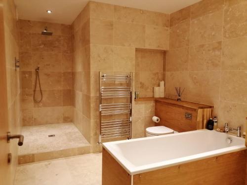 y baño con bañera, aseo y ducha. en Kilbowie Retreat en Oban