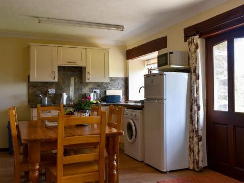 a kitchen with a table and a white refrigerator at Stable Cottage - Uk12088 in Saint Endellion