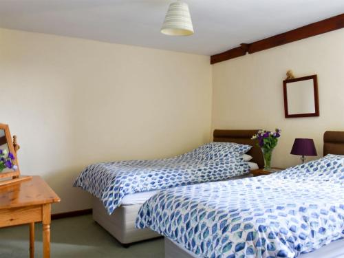 a bedroom with two beds with blue and white sheets at Stable Cottage - Uk12088 in Saint Endellion