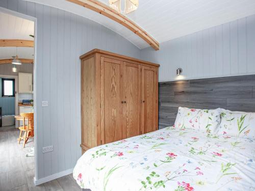 a bedroom with a bed and a wooden headboard at Moor Hen Shepherd Hut - Uk33888 in Cullompton