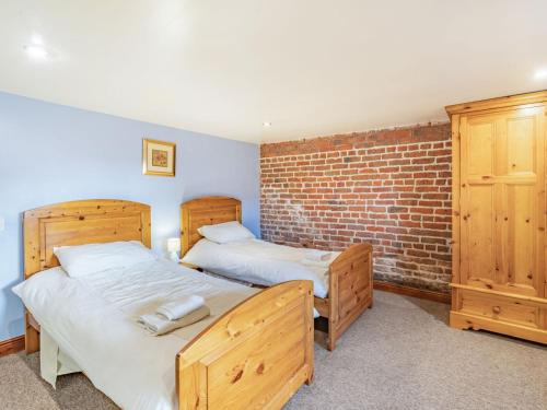 sypialnia z 2 łóżkami i ceglaną ścianą w obiekcie The Barn w mieście Poulton le Fylde