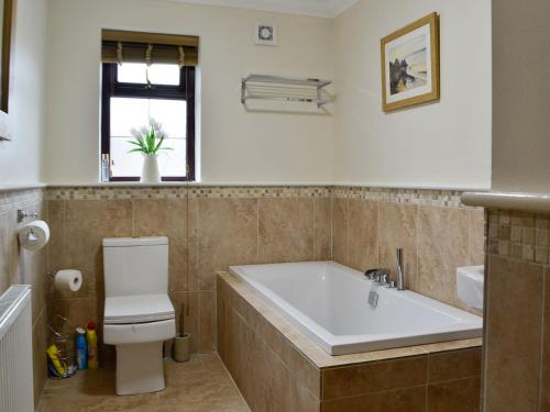 a bathroom with a tub and a toilet and a sink at Ty Glyndwr in Ystalyfera