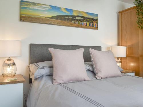 a bedroom with a bed with two lamps and a painting at Lawn Vista Cabin in Barnstaple