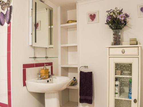 a white bathroom with a sink and a mirror at Withymead Cottage in Withypool