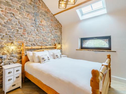 a bedroom with a stone wall and a bed at The Barnacle Goose - Uk35261 in Bowness-on-Solway