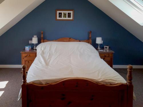 1 dormitorio con 1 cama con pared azul en Herons Nest, en Bourton on the Water