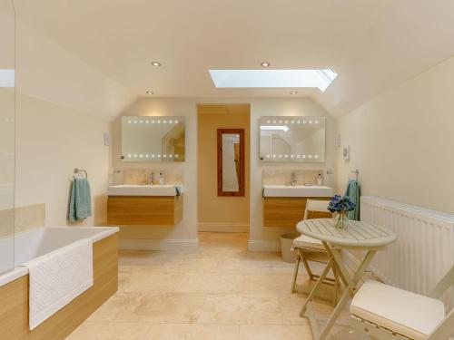 een badkamer met 2 wastafels, een bad en een tafel bij The Clock House in Bisley