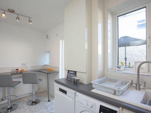 a white kitchen with a sink and a window at Suzies Pad in Torquay