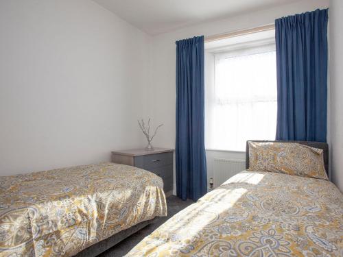 a bedroom with two beds and a window with blue curtains at Suzies Pad in Torquay