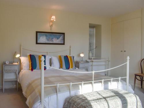 a bedroom with a white bed with colorful pillows at Coachmans Close in Milverton