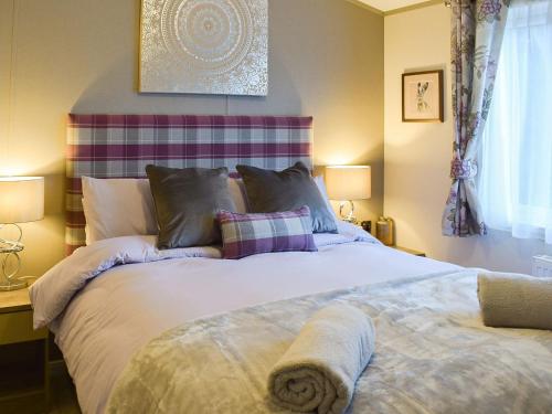 a bedroom with a large white bed with two lamps at Riverside Lodge in Auchterarder