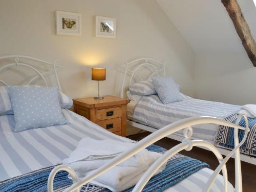 a bedroom with two beds and a table with a lamp at Swallow Barn in Torpenhow