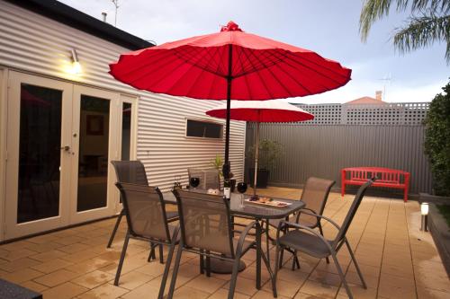 - une table et des chaises avec un parasol rouge sur la terrasse dans l'établissement Lotte's Cottage, à Broken Hill