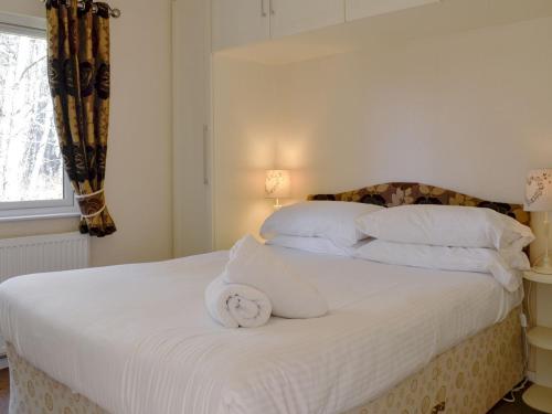 białe łóżko z ręcznikiem na górze w obiekcie Lodge F- Uk33092 w mieście Dinnet