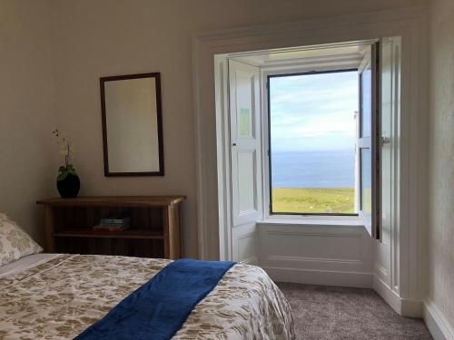 a bedroom with a window with a view of the ocean at Ballygroggan Farmhouse - Uk35208 in Machrihanish