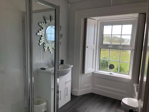 a bathroom with a sink and a mirror and a window at Ballygroggan Farmhouse - Uk35208 in Machrihanish