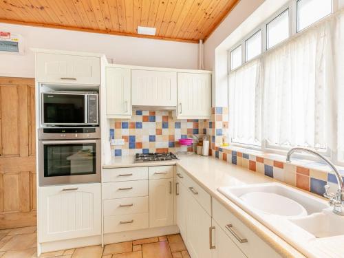a kitchen with white cabinets and a sink and a window at Summer House in Sutton on Sea