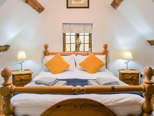 a bedroom with a wooden bed with orange pillows at Waen Farm Cottage in Tremeirchion