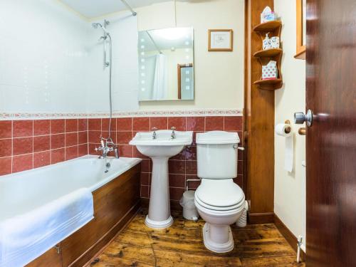 a bathroom with a toilet and a sink and a tub at Ashby Cottage in Long Compton