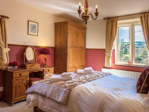 a bedroom with a bed and a dresser and a mirror at Ashby Cottage in Long Compton