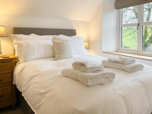 uma cama branca com toalhas e uma janela em Smardale Cottage em Crosby Garrett
