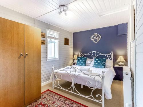 a bedroom with a white bed and a blue wall at Holly Tree Cottage in Tain
