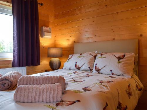 sypialnia z łóżkiem z drewnianą ścianą w obiekcie Pheasant Lodge - Uk33402 w mieście Hungerton