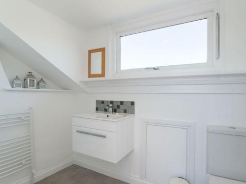 eine weiße Küche mit einem Waschbecken und einem Fenster in der Unterkunft Edenholme in Robin Hood's Bay