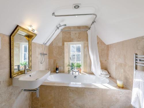 a bathroom with a tub and a sink and a mirror at Gardeners Cottage - Uk35774 in Fulbeck