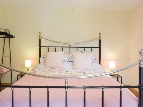 Brechfa的住宿－Typicca Farmhouse，一间卧室配有带粉色床单和枕头的金属床。