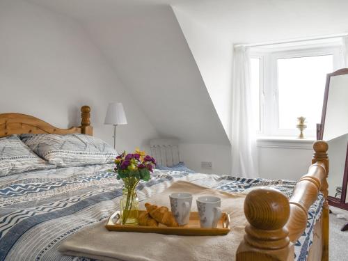 a tray of bread and two cups on a bed at Seaton Cottage in Collieston