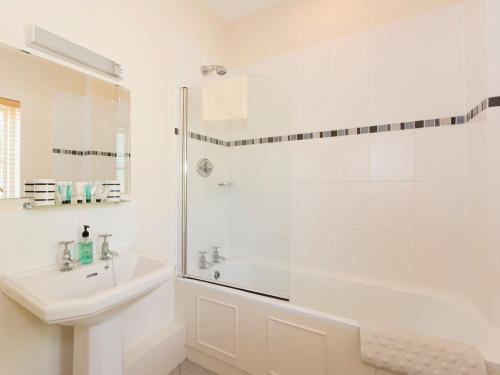 a white bathroom with a shower and a sink at Graham Cottage in Thurning