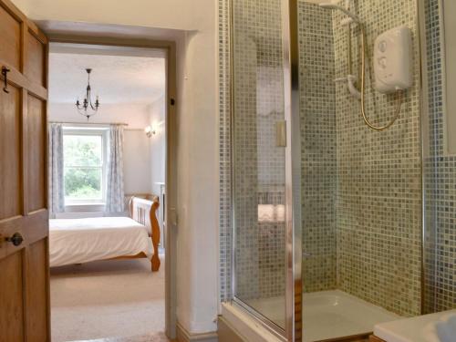 a bathroom with a shower and a tub and a bedroom at Thorn Cottage in Spark Bridge
