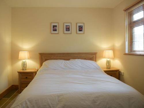 a bedroom with a white bed with two lamps at Oak Lodge in Edwin Loach