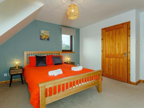 um quarto com uma grande cama laranja e 2 almofadas em The Big Hoose em Achnahanat