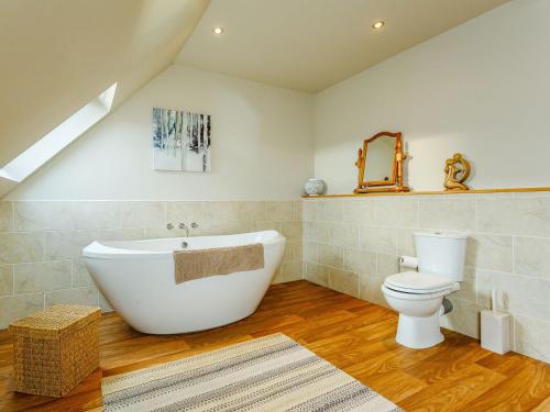 a bathroom with a white tub and a toilet at The Big Hoose in Achnahanat