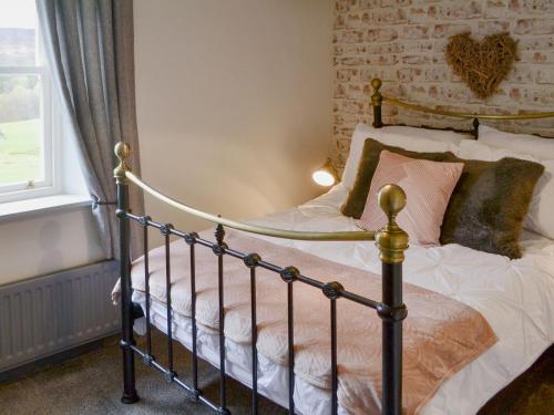 a bed in a bedroom with a brick wall at Townhead Cottage in Alwinton