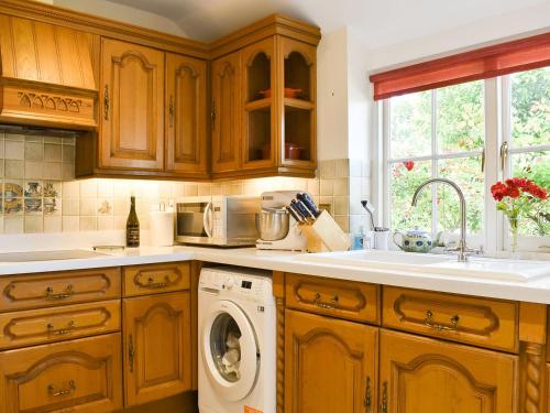 a kitchen with wooden cabinets and a washing machine at Buckshaw Gate in Holwell