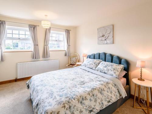 a bedroom with a large bed and two windows at Lilium Cottage in North Somercotes