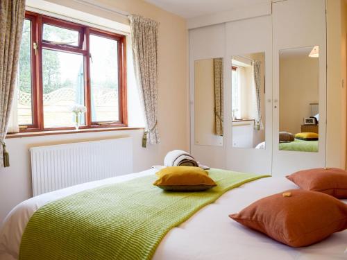 1 dormitorio con cama con almohadas y espejo en The Byre en Pencombe